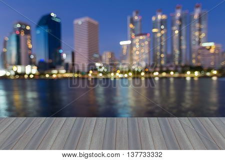 Opening wooden floor, abstract blurred city lights waterfront  at twiligh