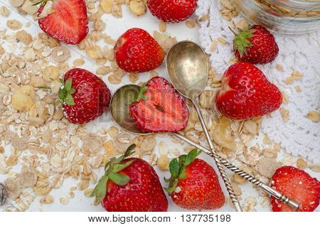 Ripe and tasty strawberries with scattered muesli on white background