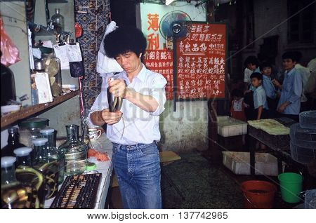 GUANGZHOU / CHINA - CIRCA 1987: A vendor holds a snake in Guangzhou's Qingping Market.