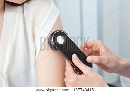 Doctor examining birthmarks and moles on a female patient (examination of birthmarks)