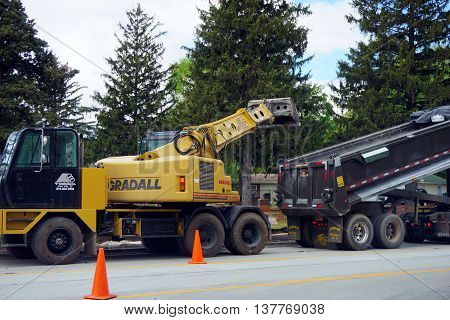 PLAINFIELD, ILLINOIS / UNITED STATES - MAY 4, 2016: A 
yellow Gradall XL 4100 IV Hydraulic Excavator places dirt into a dumptruck at a road construction project on Renwick Road in Plainfield.