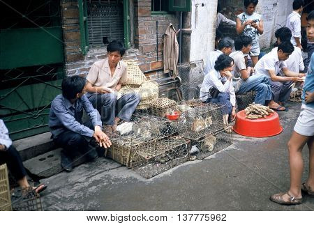 GUANGZHOU / CHINA - CIRCA 1987: Vendors sell rabbits and cats in cages in Guangzhou's Qingping Market.