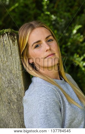 Close-up Of Blonde Leaning Against Wooden Gatepost
