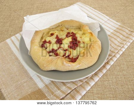 Pizza bread street food with cheese and ham in greaseproof paper bag
