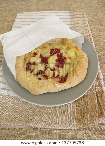 Pizza bread street food with cheese and ham in greaseproof paper bag