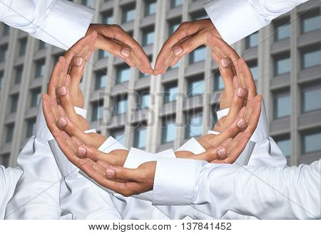 Hand of men concatenation a heart shape and have Skyscraper of background.