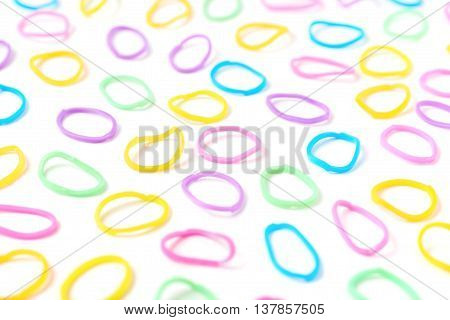 Surface covered with multiple colorful resin loom bands over the white background, shallow depth of field composition