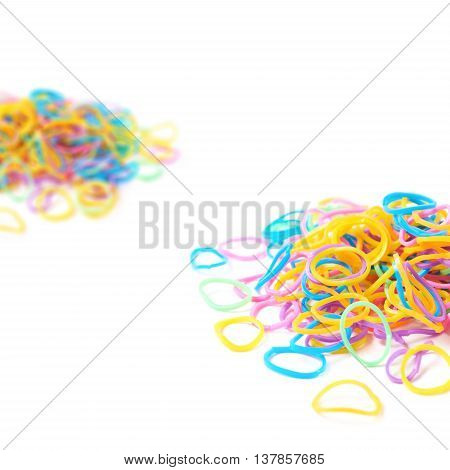 Pile of multiple colorful rubber toy loom bands isolated over the white background, close-up crop fragment foreshortening
