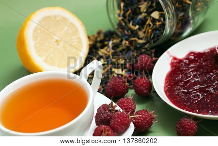 Tea lemon jam and red raspberry berries on a green