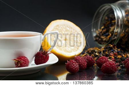 Tea lemon and red raspberry berries on a black