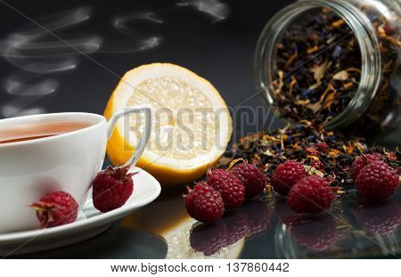 Tea lemon and red raspberry berries on a black