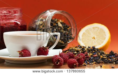 Tea lemon jam and red raspberry berries on a orange background