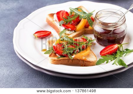 French toast with fresh strawberries, peaches and arugula, poured with maple syrup
