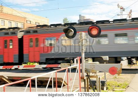 A passenger train moves along the route.And the railway crossing was closed.