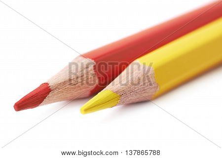 Two red and yellow colored drawing pencils composition isolated over the white background, close-up crop fragment