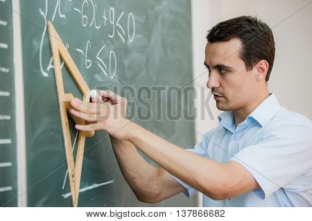 Young teacher or student draw triangle on a blackboard with formula.