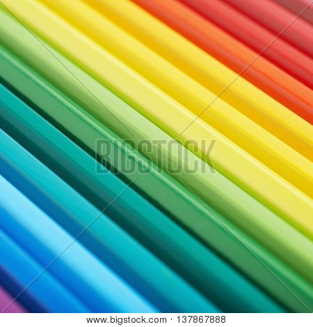 Multiple colorful color pencils composition arranged in a line to form a rainbow gradient, close-up crop fragment