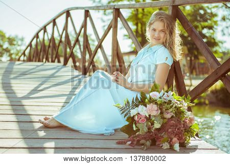girl in a blue dress. Next to a bouquet of flowers
