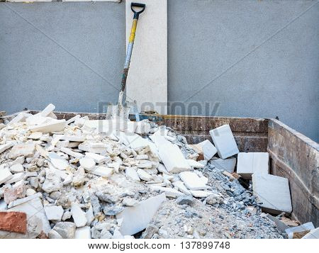 Trash construction building demolition waste hard work concept. Spade in pile of rubble. Manual labor tool sticking out from debris.