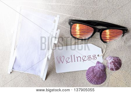Sunny Summer Label With English Text Wellness. Flat Lay View. Summer Decoration With Deck Chair, Seashells And Sunglasses. Greeting Crad With Sand Background
