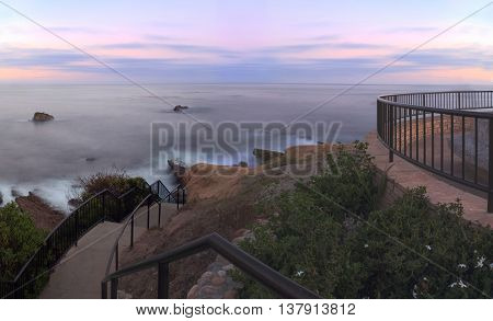 Steps from Heisler Park leading down to the sand and ocean in Laguna Beach, California at sunset.