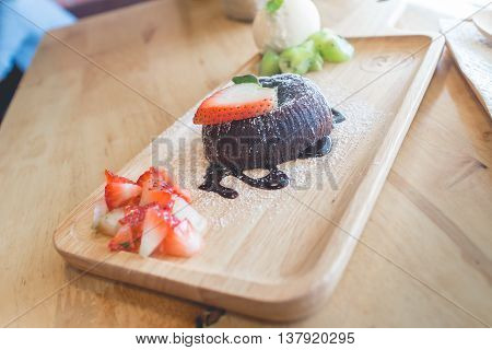 chocolate lava cake with vamilla ice cream and strawberry. chocolate lava on wood plate. chocolate lava. Hot chocolate pudding with fondant centre.(selective focus)