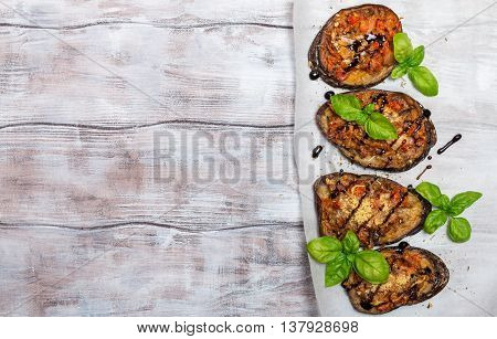 Baked eggplant stuffed with vegetables and cheese with addition aromatic herbs and sauce on paper. Delicious vegetarian dish. top view, sopy space