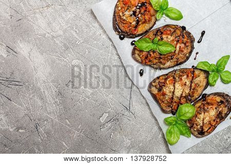 Baked eggplant stuffed with vegetables and cheese with addition aromatic herbs and sauce on paper. Delicious vegetarian dish. top view, sopy space