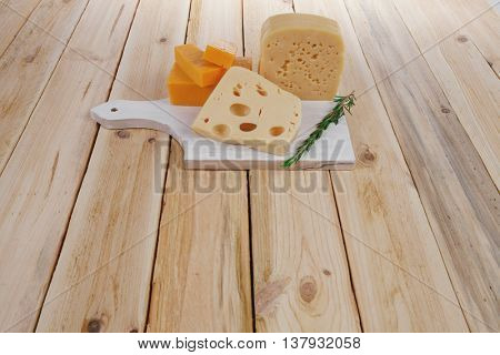 various types of fresh raw aged delicatessen cheese on white plate over light wooden table cheddar edam swiss