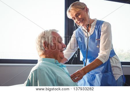 Nurse using stethoscope to take care of a senior man in a retirement home