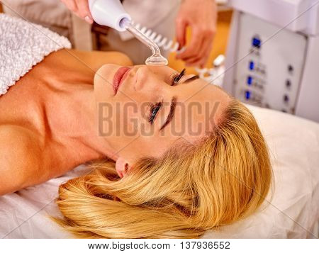 Young woman receiving electric darsonval facial massage at beauty salon. Anti-aging massage.