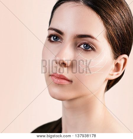 Young female face with clean fresh skin over biege background. Antiaging concept