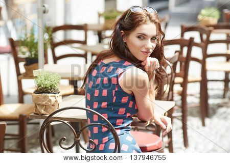 Stylish  woman, wearingsummer dresst,  posing at city cafe terrace, traveling clone, sunny day.