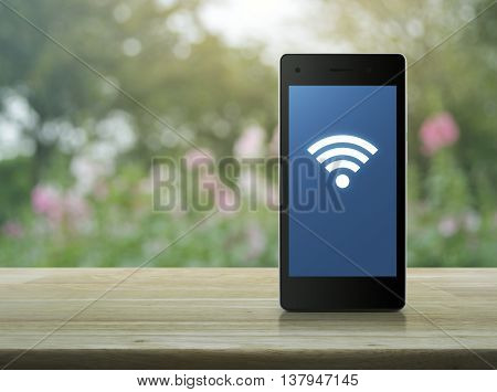 Wi-fi connection icon on modern smart phone screen on wooden table over blur pink flower and tree Technology and internet concept