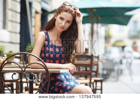 Stylish  woman, wearingsummer dresst,  posing at city cafe terrace, traveling clone, sunny day.