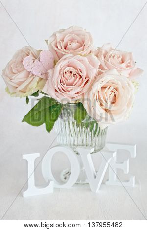 Pink roses flowers in a vase and letters 