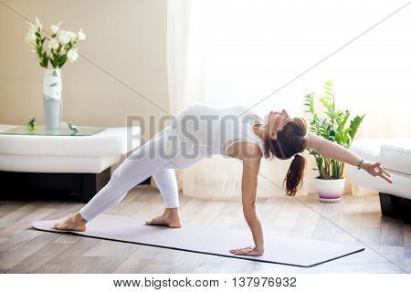 Pregnant Woman Doing Camatkarasana Yoga Pose At Home