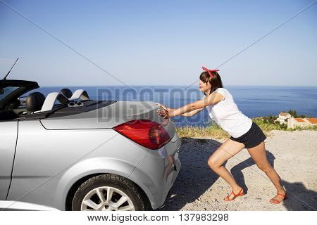 Young woman push the car runs out of gas.