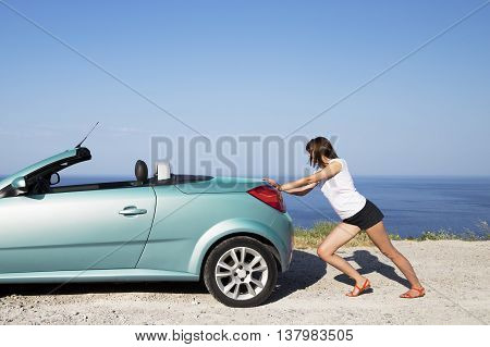 Young woman push the car runs out of gas.