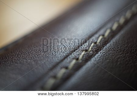 Macro detail of a white thread stitching black and brown stitched leather wallet