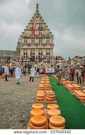 Gouda, southern Netherlands - June 29, 2017. Stacks of cheeses for sale at the Market Square fair and gothic City Hall in Gouda. Very popular day trip destination, is famous for its tasty Gouda cheese