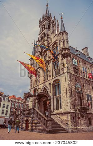 Gouda, Southern Netherlands - June 29, 2017. People At Gothic City Hall And Flags On Cloudy Day In G