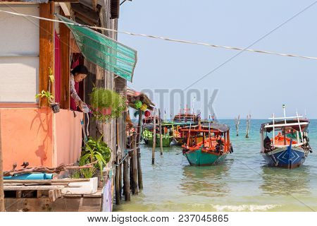 Koh Rong Island, Cambodia - 07 April 2018: Sea View With Boat, House On Piles And Woman Watering Flo