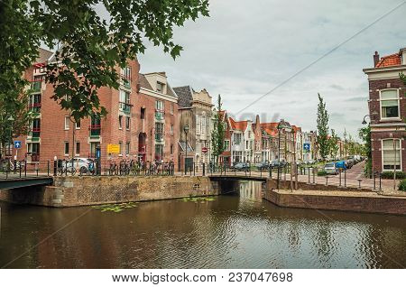 Gouda, Southern Netherlands - June 29, 2017. Walled Canal With Bascule Bridge, Trees And Brick Build