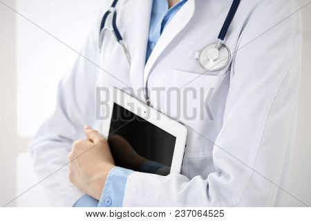 Woman Doctor Using Tablet Computer While Standing Straight In Hospital Closeup. Healthcare, Insuranc