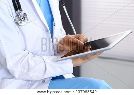 Woman Doctor Using White Tablet Computer While Working In Hospital.