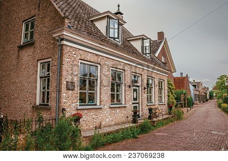 Charming And Quiet Alley With Brick Rustic Houses And Greenery In Cloudy Day At Drimmelen. A Lovely 