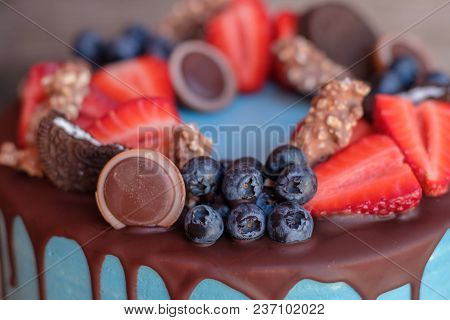 Beautiful Homemade Cake With Blue Cream And Chocolate Glaze, Decorated With Strawberries And Blueber