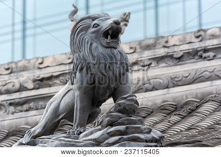 Lion Sculpture On Daci Buddhist Temple Roof Against Modern Building In Chengdu, China