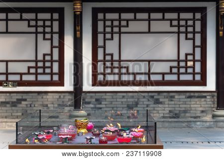 Candles Burning In Daci Buddhist Temple Roof Against Modern Building In Chengdu, China